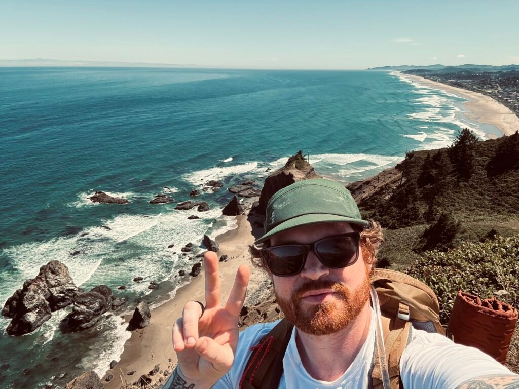 Michael Chasteen at the beach with a peace sign showing signs of love and comfort. Beautiful background of Lincoln City, Oregon